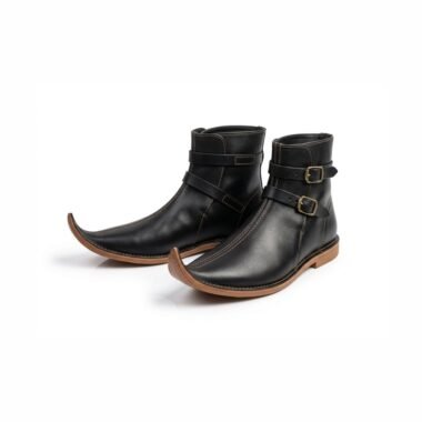 Pair of black medieval pointed boots with two brass buckle straps on white background