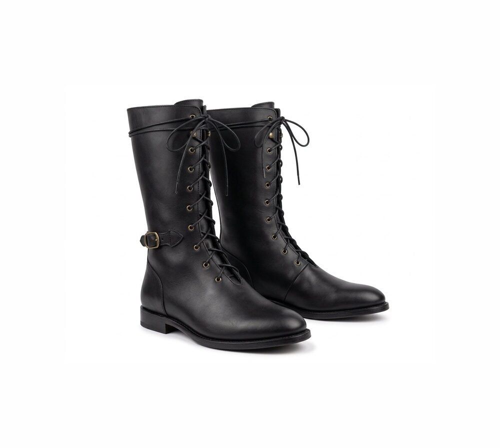 Black medieval riding boots with brass eyelet lacing and ankle buckle strap — front three-quarter view