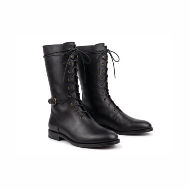 Black medieval riding boots with brass eyelet lacing and ankle buckle strap — front three-quarter view